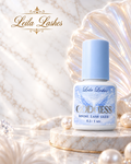 Adeziv GODDESS Leila Lashes pentru extensii de gene, flacon alb cu capac albastru, pe fundal decorativ cu perle.